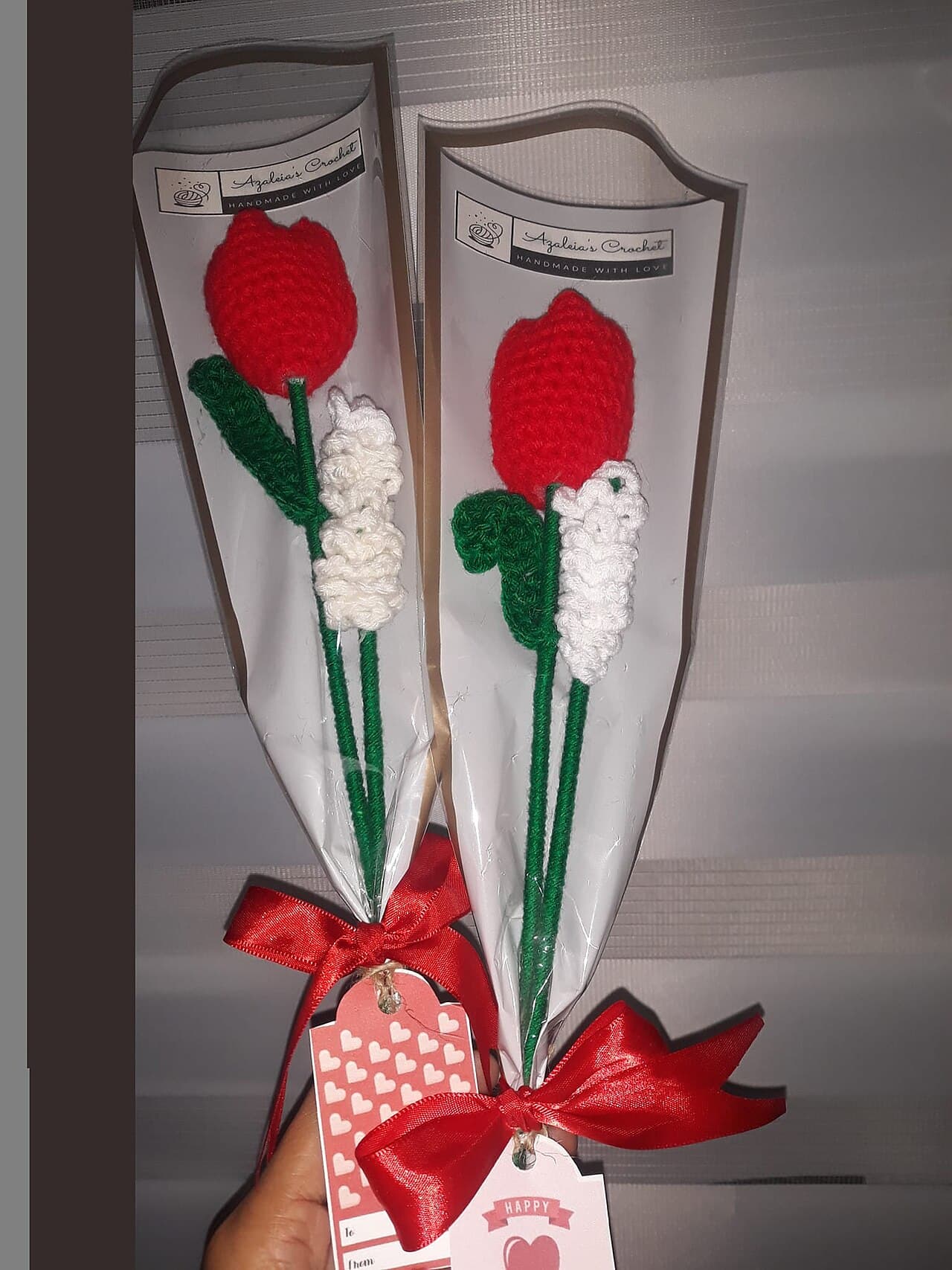 Two red crochet tulips and white crochet flowers tied with red ribbons